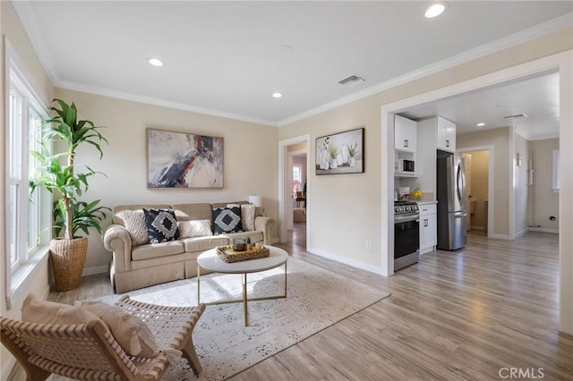 living room with light hardwood / wood-style floors, crown molding, and a healthy amount of sunlight