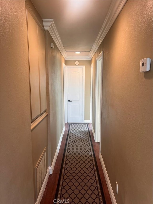 corridor with dark wood-style flooring, visible vents, crown molding, and baseboards