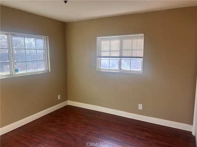 unfurnished room with a healthy amount of sunlight, dark wood-style floors, and baseboards