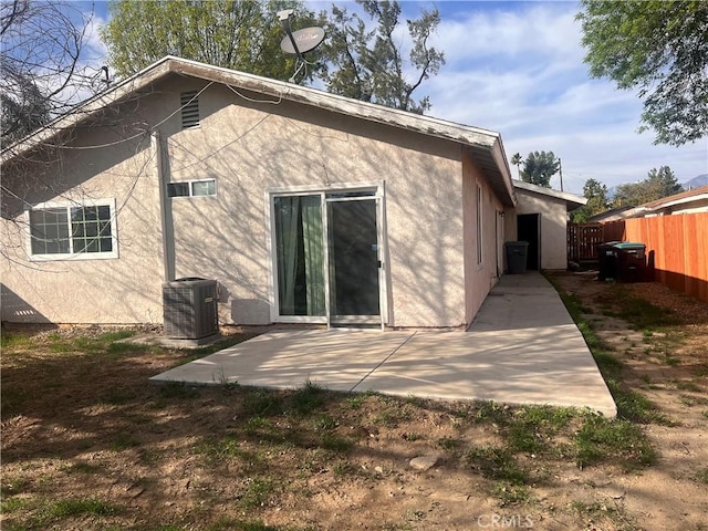 rear view of property with a patio, central air condition unit, fence, and stucco siding