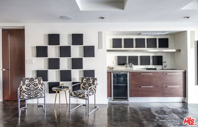 bar with sink, dark brown cabinets, and wine cooler