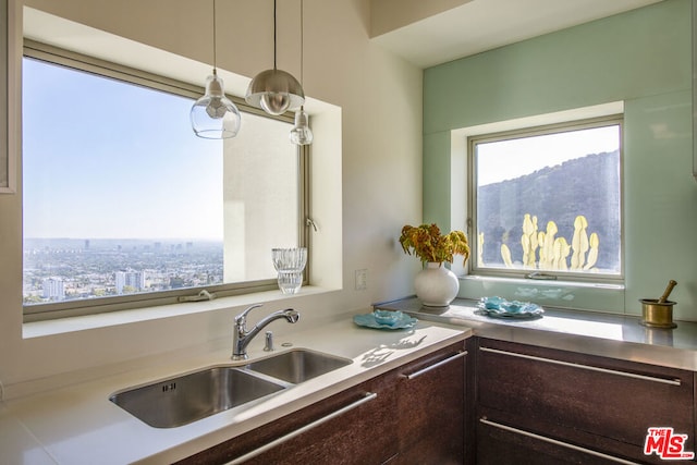 kitchen with decorative light fixtures, sink, and dark brown cabinetry