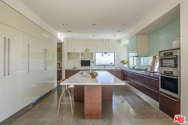 kitchen featuring a kitchen island, sink, a kitchen breakfast bar, and hanging light fixtures