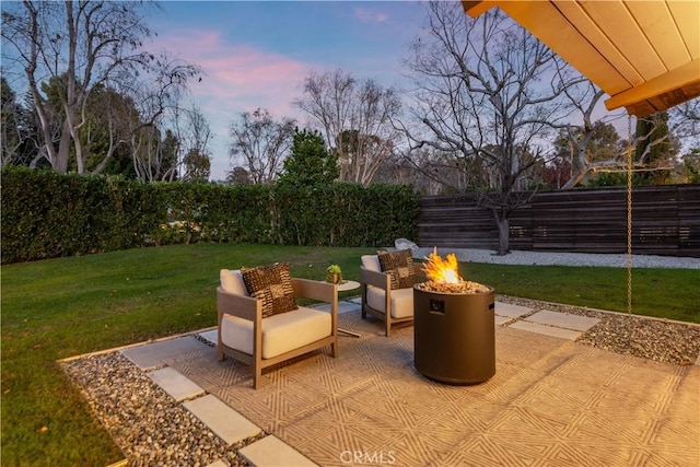 patio terrace at dusk featuring an outdoor fire pit and a yard