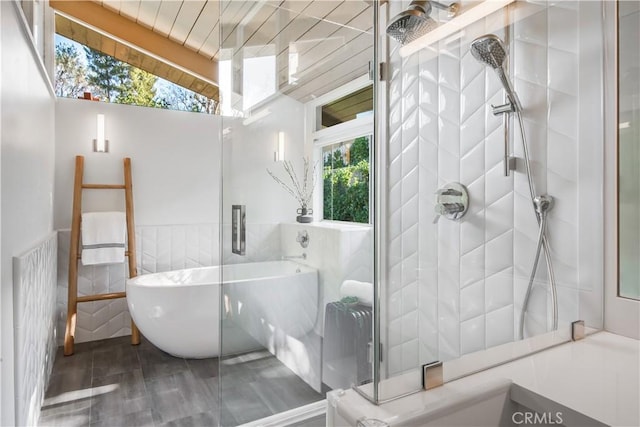 bathroom with plenty of natural light, tile walls, independent shower and bath, and vaulted ceiling