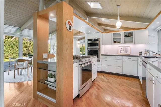 kitchen with white cabinets, decorative light fixtures, lofted ceiling with skylight, and stainless steel appliances