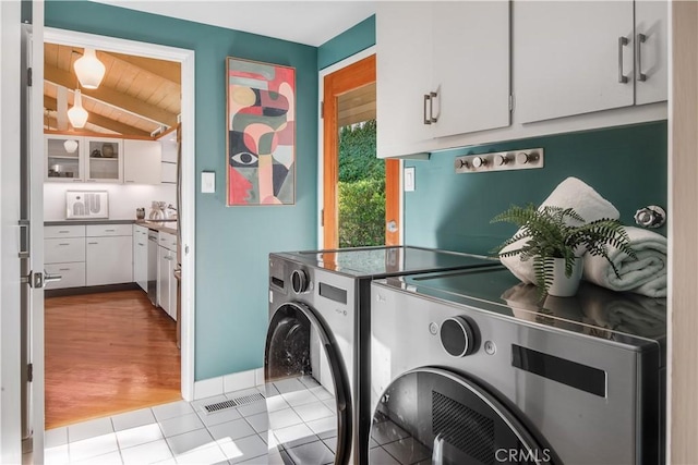 laundry area with cabinets, light tile patterned floors, separate washer and dryer, and wood ceiling