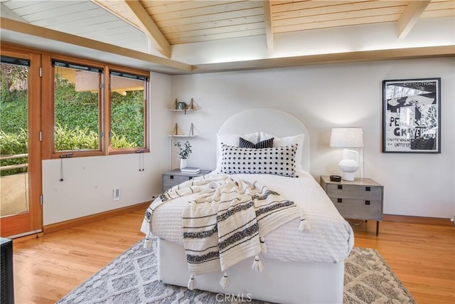 bedroom featuring beamed ceiling, light hardwood / wood-style flooring, wooden ceiling, and multiple windows