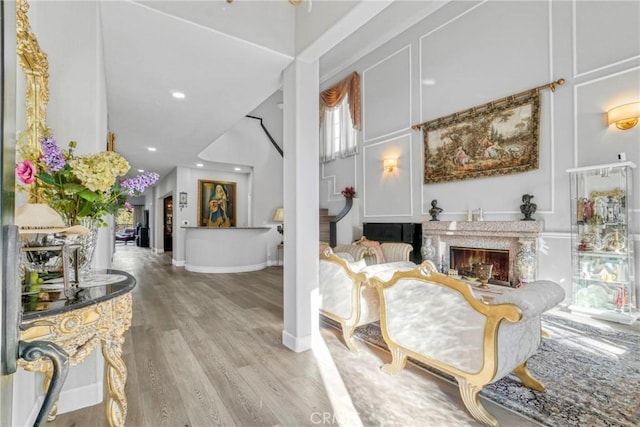 interior space with a towering ceiling, a premium fireplace, and light wood-type flooring