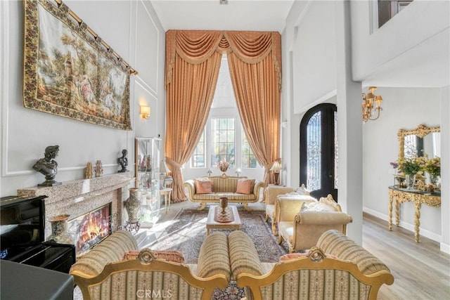 sitting room featuring a premium fireplace, a high ceiling, and light wood-type flooring