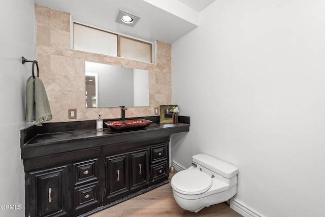 bathroom with vanity, hardwood / wood-style flooring, tasteful backsplash, and toilet