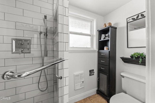 bathroom with a tile shower, toilet, and tile patterned floors