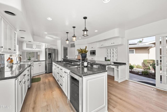 kitchen with white cabinets, a center island, beverage cooler, and appliances with stainless steel finishes