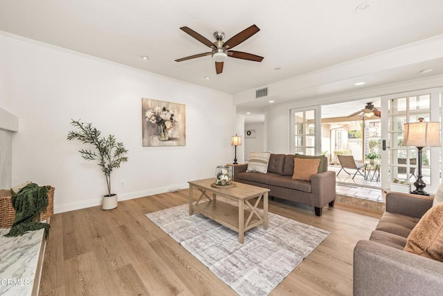 living room featuring ceiling fan, ornamental molding, and light wood-type flooring