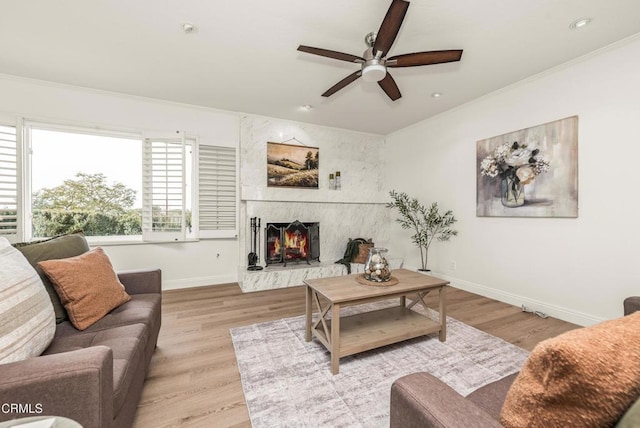 living room featuring a large fireplace, light wood-type flooring, and crown molding