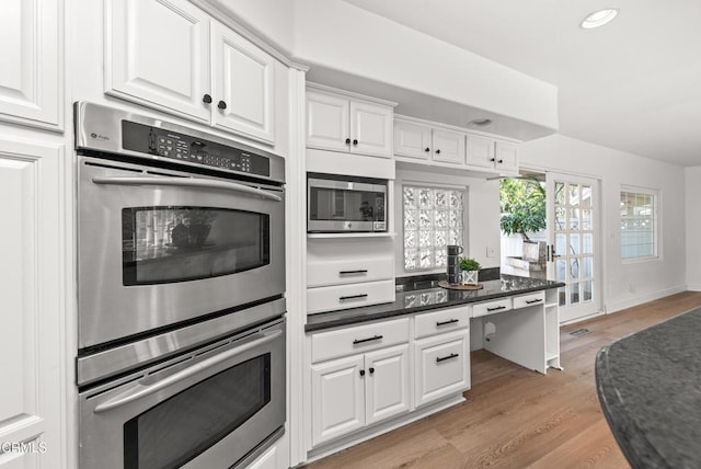 kitchen with light hardwood / wood-style floors, white cabinets, stainless steel appliances, and built in desk