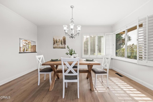 dining room with visible vents, ornamental molding, baseboards, and wood finished floors