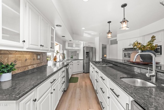 kitchen featuring a sink, white cabinets, appliances with stainless steel finishes, light wood-type flooring, and backsplash