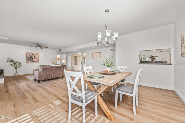 dining area featuring ceiling fan with notable chandelier, baseboards, and light wood finished floors