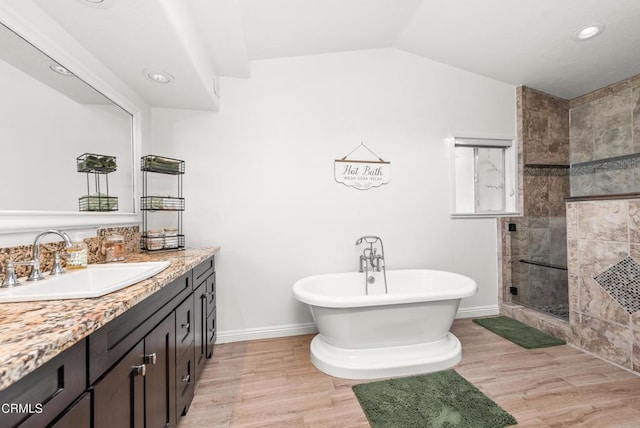 bathroom with vaulted ceiling, a tile shower, wood finished floors, a soaking tub, and vanity