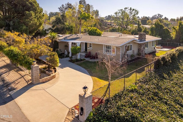 view of front facade featuring concrete driveway, fence private yard, and a front yard