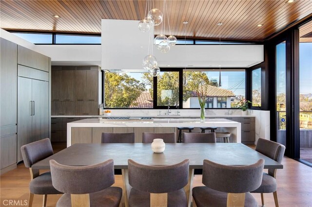 dining room featuring wood ceiling, plenty of natural light, sink, and light wood-type flooring