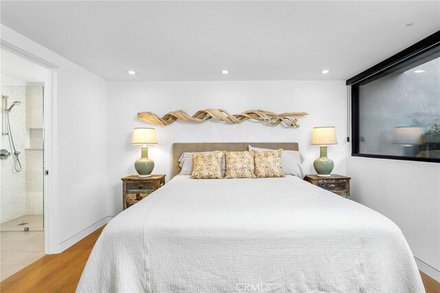 bedroom with ensuite bathroom and light hardwood / wood-style flooring