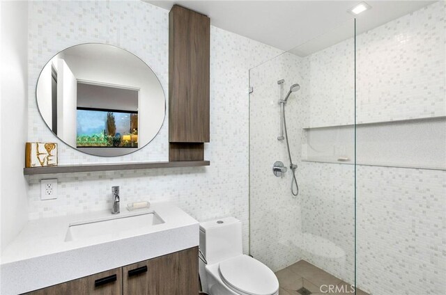 bathroom with vanity, toilet, decorative backsplash, and a tile shower