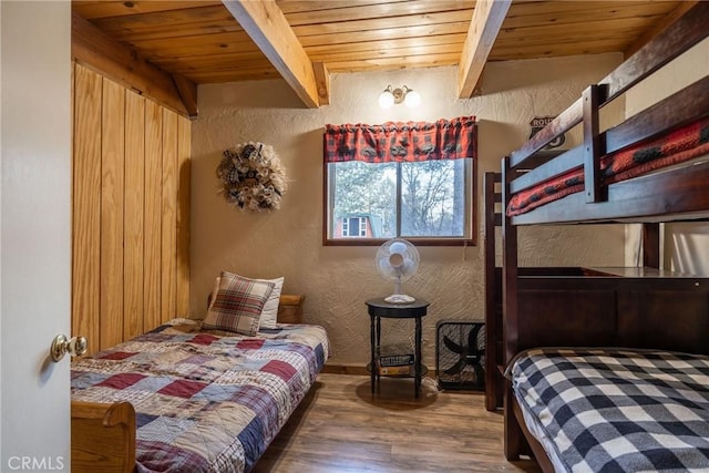 bedroom featuring beamed ceiling, wood-type flooring, and wooden ceiling