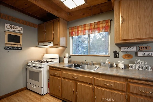 kitchen featuring sink, beam ceiling, gas range gas stove, and light wood-type flooring