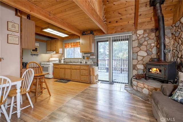 kitchen with white gas stove, wooden ceiling, light wood-type flooring, a wood stove, and beamed ceiling