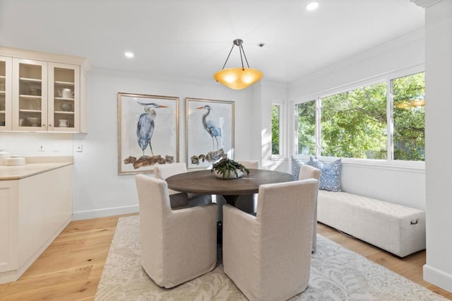 dining room with crown molding and light hardwood / wood-style flooring