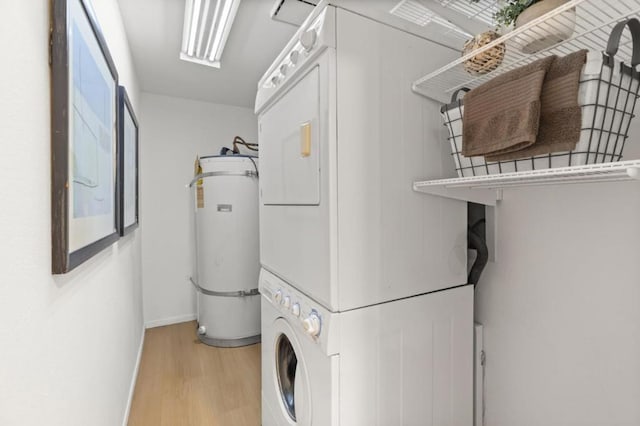 washroom featuring stacked washer / dryer, light hardwood / wood-style floors, and water heater