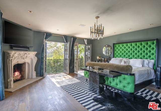 bedroom featuring hardwood / wood-style floors, access to outside, and an inviting chandelier