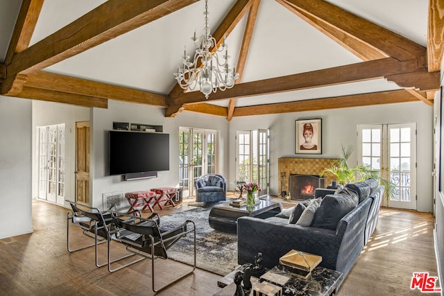 living room with hardwood / wood-style floors, french doors, an inviting chandelier, high vaulted ceiling, and a tile fireplace