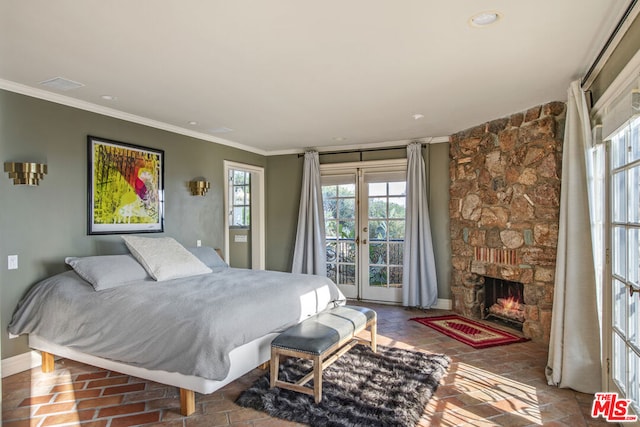 bedroom with crown molding, access to outside, a stone fireplace, and french doors