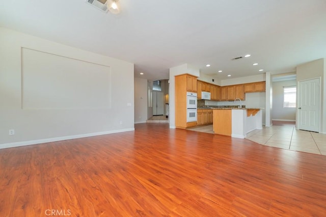 unfurnished living room with sink and light wood-type flooring