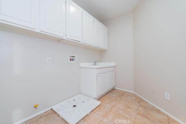 washroom with sink, light tile patterned floors, hookup for a washing machine, and cabinets