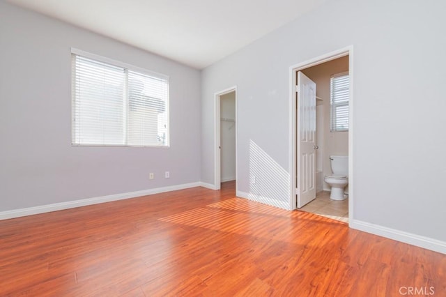 unfurnished bedroom featuring a walk in closet, light hardwood / wood-style floors, a closet, and ensuite bathroom