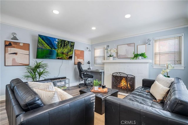 living room with ornamental molding, a brick fireplace, and light hardwood / wood-style flooring