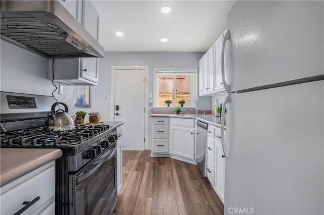 kitchen featuring dark wood-type flooring, sink, ventilation hood, stainless steel appliances, and white cabinets