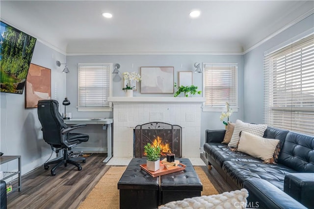 living room with hardwood / wood-style flooring, ornamental molding, and a tile fireplace