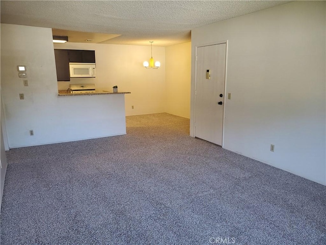 unfurnished living room with a chandelier, a textured ceiling, and carpet flooring