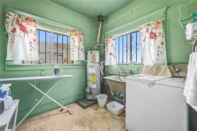 bathroom featuring sink, water heater, and washer / dryer