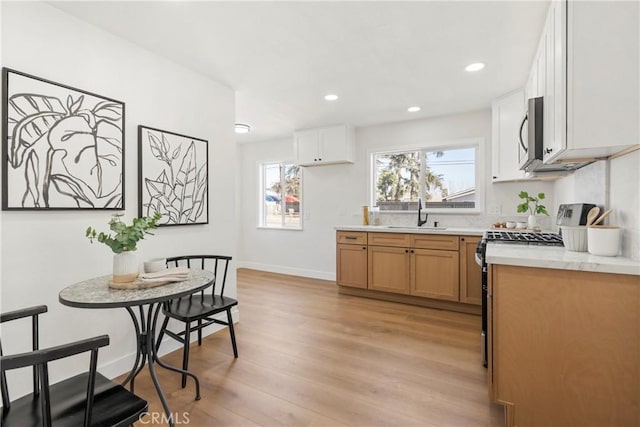 kitchen with sink, light hardwood / wood-style floors, white cabinets, and appliances with stainless steel finishes