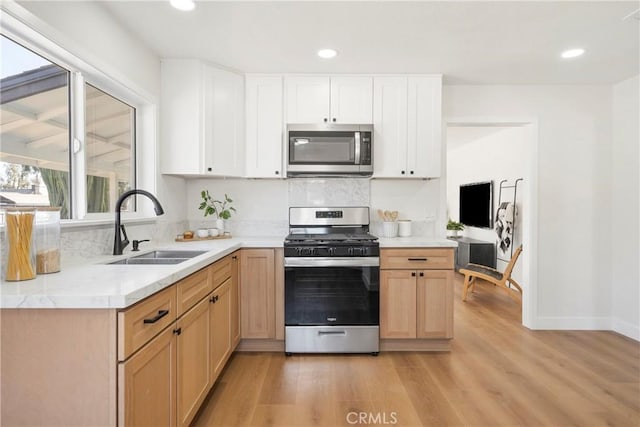 kitchen with white cabinetry, sink, light hardwood / wood-style flooring, and appliances with stainless steel finishes