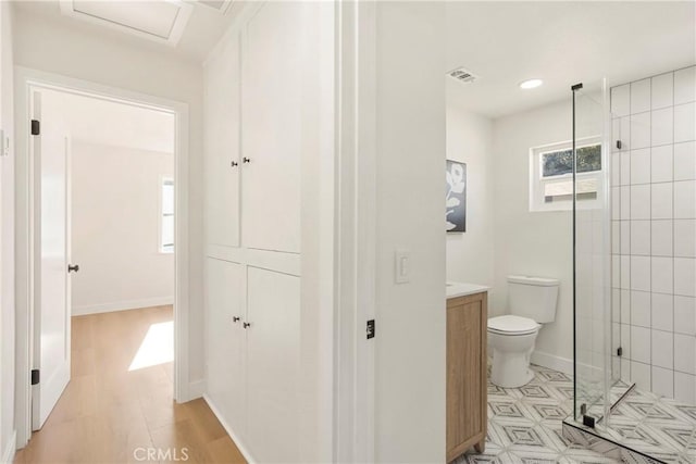 bathroom with hardwood / wood-style flooring, vanity, toilet, and a tile shower