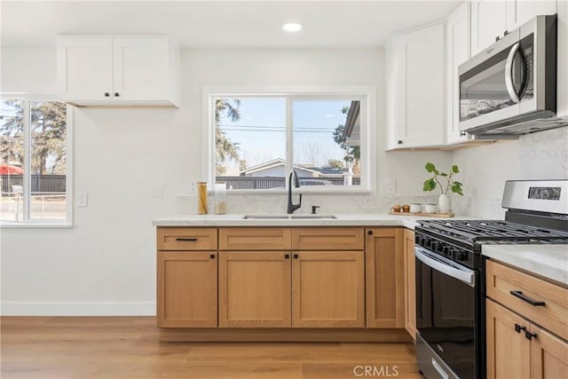 kitchen featuring stainless steel appliances, sink, a wealth of natural light, and white cabinets