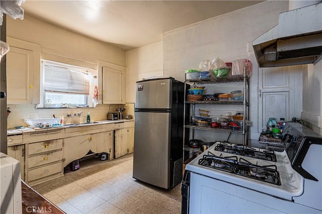 kitchen with exhaust hood, sink, backsplash, white gas stove, and stainless steel fridge