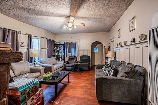 living room with ceiling fan, a textured ceiling, and dark hardwood / wood-style flooring